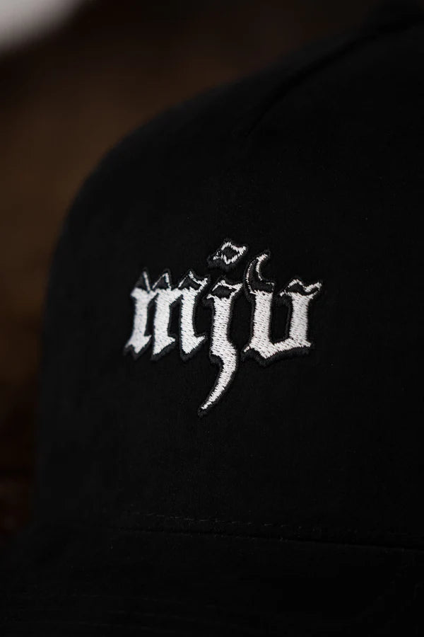 Nahaufnahme des gesticktem 'MJV' Logos in weiß auf schwarzer Kappe.