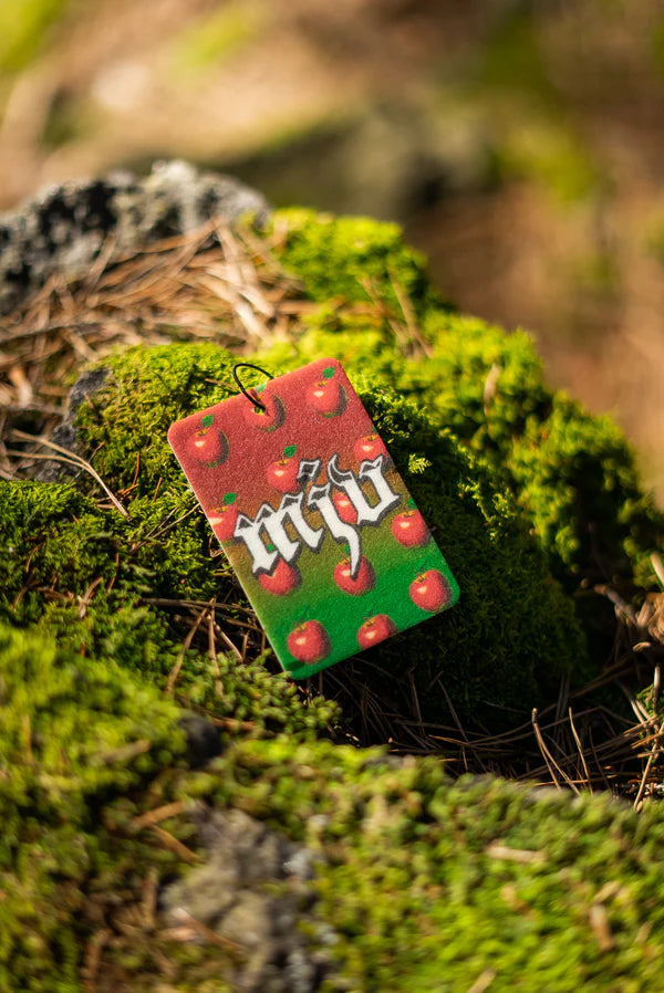 Duftbam 'Maschansker' Rückseite auf bemoostem Stein. MJV Logo in weiß auf grün-rotem Hintergrund mit Äpfel im Hintergrund. 'Maschansker' Duftbaum vom Marderjagdverein.