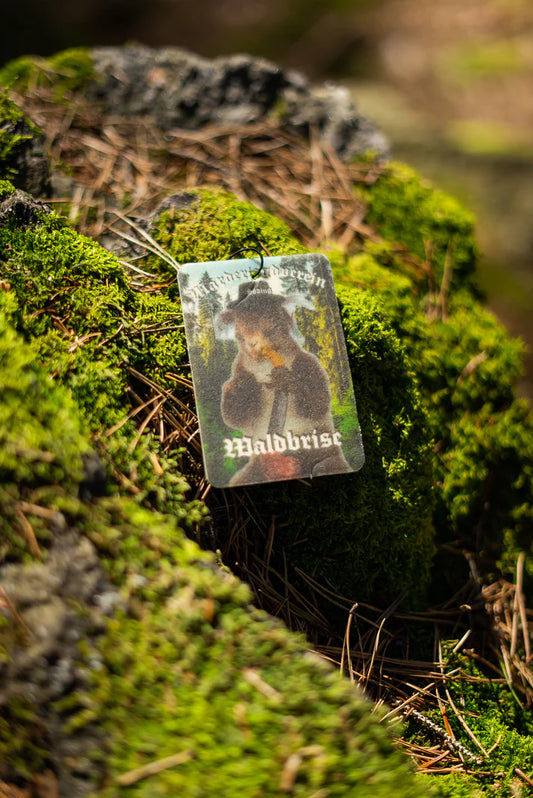 Duftbam 'Waldbrise' Vorderseite auf bemoostem Stein. MJV Logo in weiß und Marder mit Pfeife und Hut stehend im Wald. 'Waldbrise' Duftbaum vom Marderjagdverein.