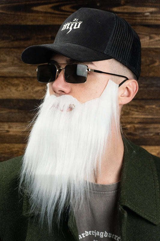 Mann trägt einen langen weißen Bart, Sonnenbrille und eine schwarze Kappe mit gesticktem weißen 'MJV' Logo.