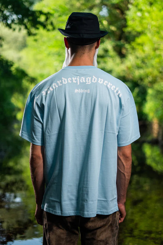 Mann mit Sonnenhut, Sonnenbrille und blauem Shirt bekleidet. Rückenansicht mit Aufdruck am blauen T-Shirt in weiß 'Marderjagdverein Söding'