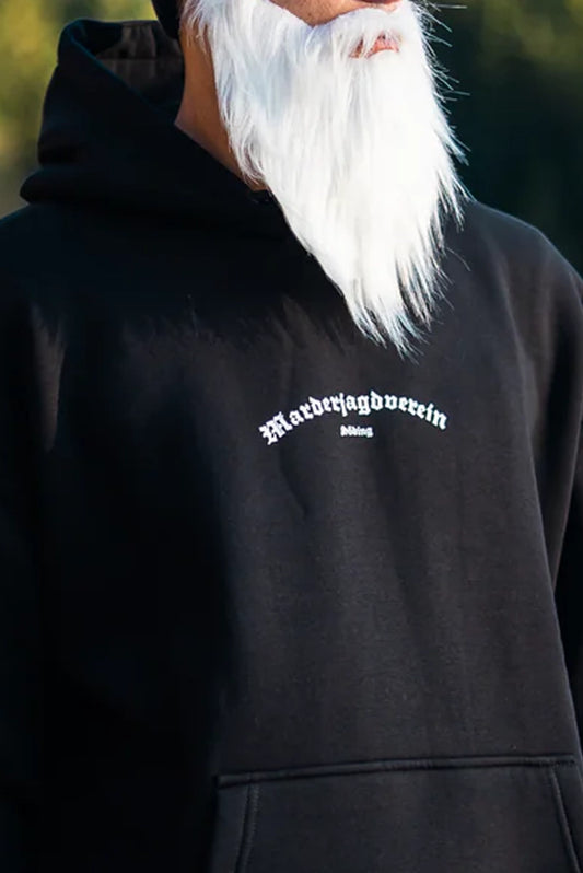 Mann mit weißem langen Bart trägt einen schwarzen Kapuzenpullover mit weißer 'Marderjagdverein Söding' Aufschrift.