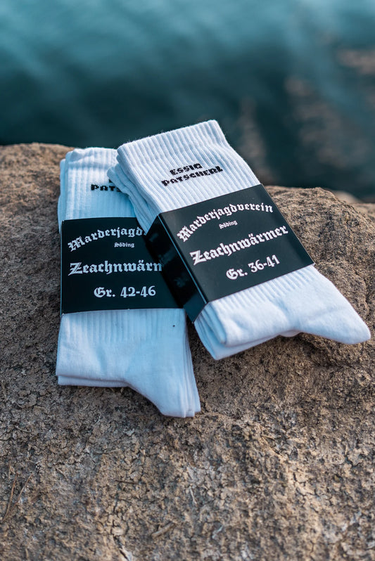 Weiße in schwarzer Banderole verpackte Sportsocken mit 'Essigpatscherl' Aufschrift in schwarz.