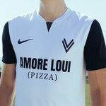 Mann trägt weißes ASK Voitsberg Trikot mit schwarzen kurzen Ärmeln mit schwarzem ASK Voitsberg Wappen auf der linken Brustseite, schwarzem Nike Swoosh auf der rechten Brustseite und Amore Loui (Pizza) Logo in schwarz über die gesamte Brust.